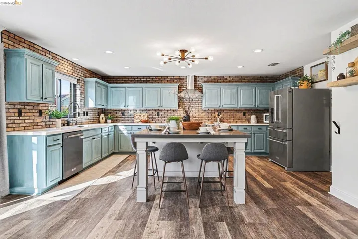 Kitchen featuring stainless steel appliances, a kitchen breakfast bar, dark wood-style floors, and light countertops