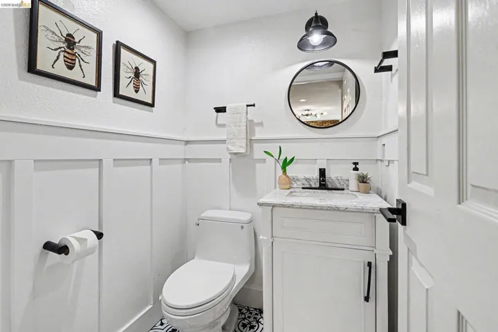 Half bath featuring vanity, a wainscoted wall, and a decorative wall