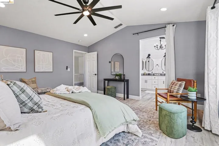 Bedroom with ceiling fan, connected bathroom, wood finished floors, and hanging lights