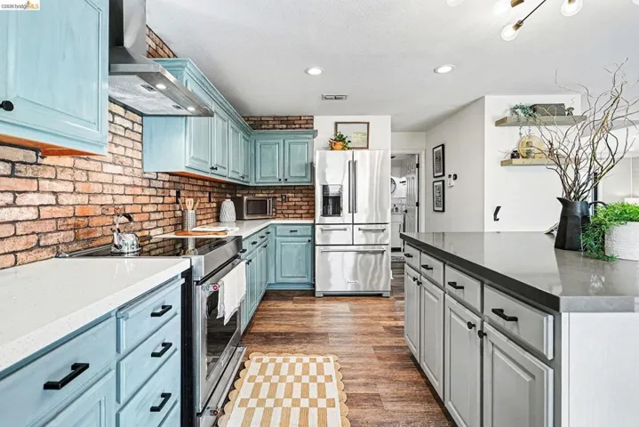 Kitchen featuring stainless steel appliances, dark stone counters, dark wood-style floors, two tone cabinets, and recessed lighting