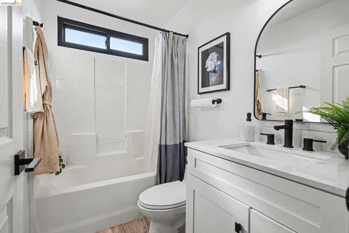 Full bathroom with shower / bath combination with curtain, vanity, and light wood-style floors