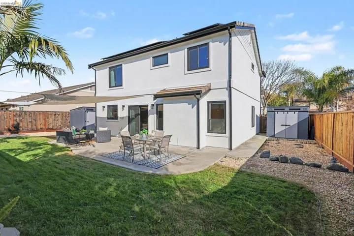 Back of house with a storage unit, a fenced backyard, a patio area, and stucco siding