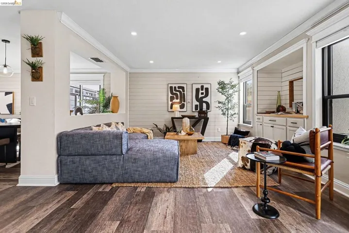 Living room with wood finished floors, wooden walls, recessed lighting, and crown molding