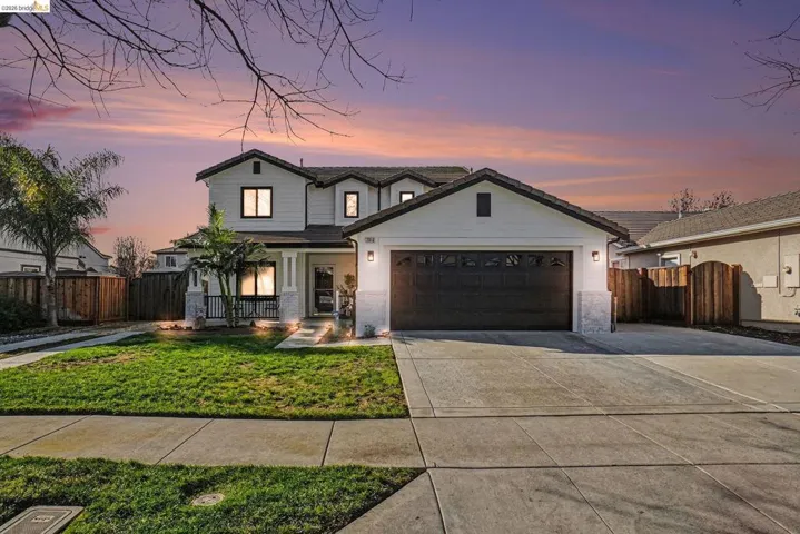 View of front of house with concrete driveway, covered porch, a tiled roof, and a garage