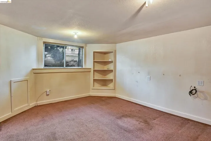 Spare room with built in features, a textured ceiling, and carpet flooring