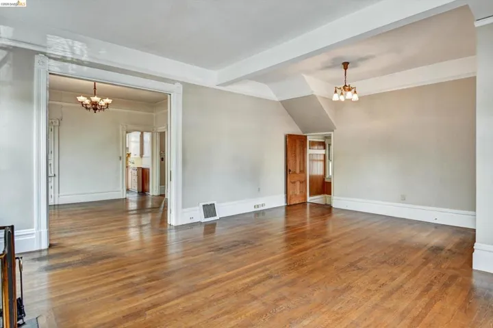 Unfurnished room featuring suspended lighting, dark wood finished floors, and lofted ceiling with beams
