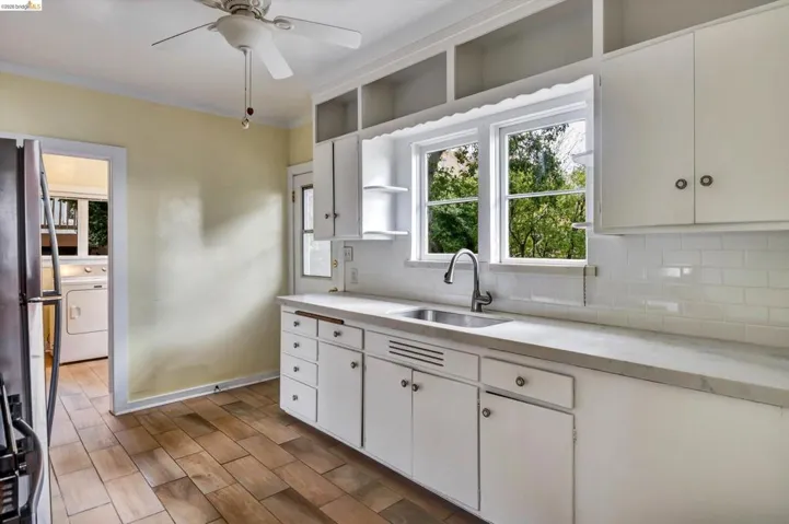 Kitchen with white cabinetry, light countertops, open shelves, wood finish floors, and crown molding