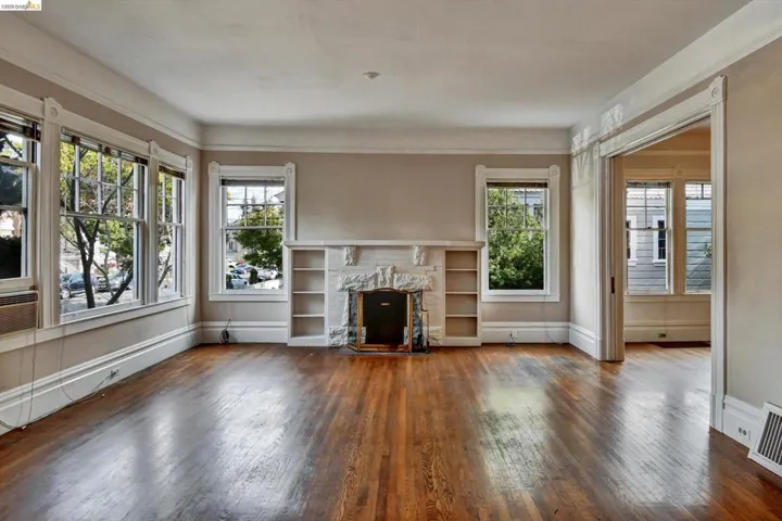 Unfurnished living room with dark wood-style flooring and a fireplace with flush hearth