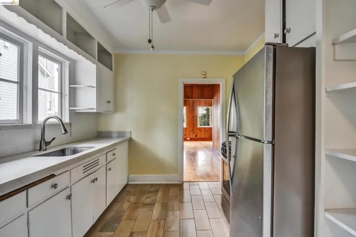 Kitchen with open shelves, white cabinetry, wood finish floors, stainless steel appliances, and crown molding