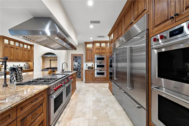 Luxury Kitchen Featuring Wolf Stainless Steel Appliances and Hand Carved Wood