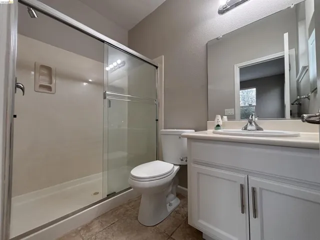 Bathroom featuring vanity, a shower stall, light tile patterned floors, and a textured wall