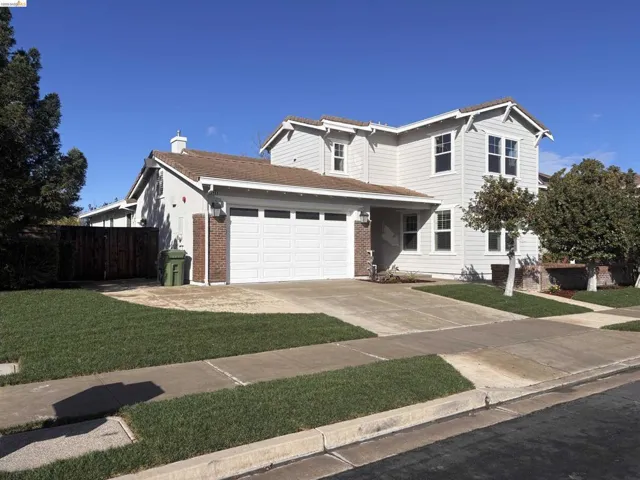 Traditional-style home with concrete driveway, a garage, brick siding, and a tile roof