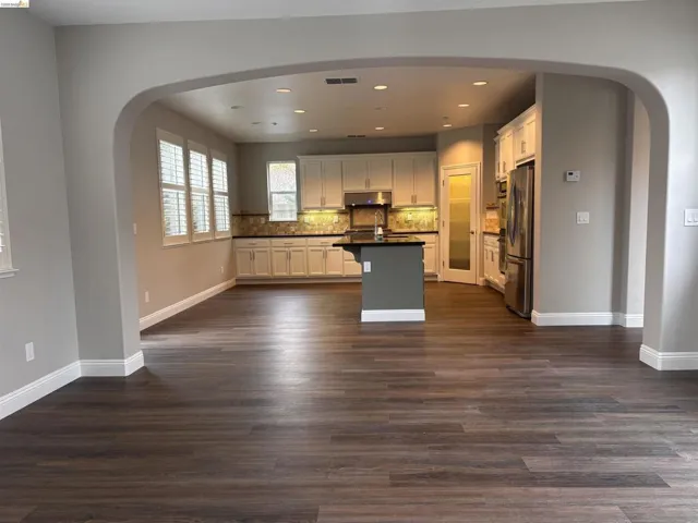 Kitchen featuring arched walkways, dark countertops, white cabinets, recessed lighting, and a kitchen island