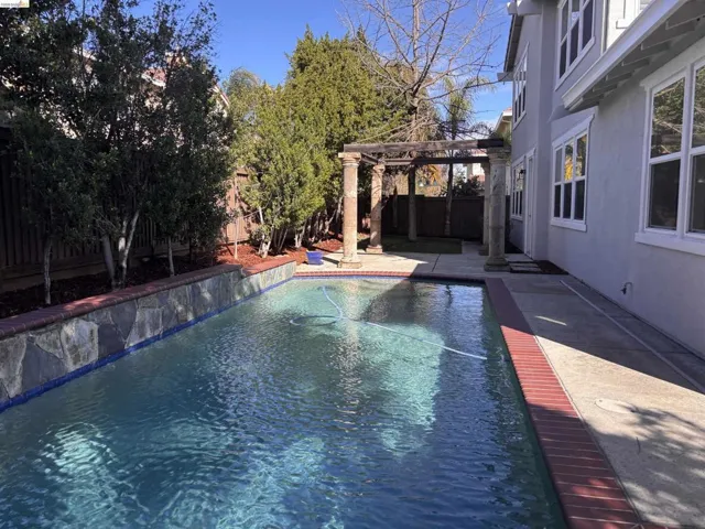 View of swimming pool with a pergola, patio surround, and a fenced backyard