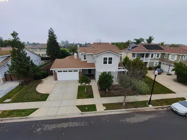 Traditional-style house featuring driveway, a garage, a residential view, a tiled roof, and a front lawn