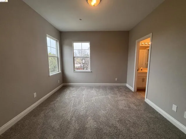Unfurnished bedroom with light colored carpet and ensuite bath
