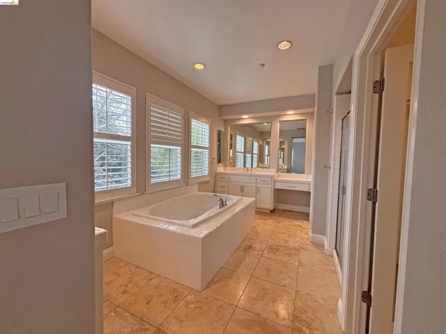 Bathroom with a shower stall, vanity, a bath, and recessed lighting