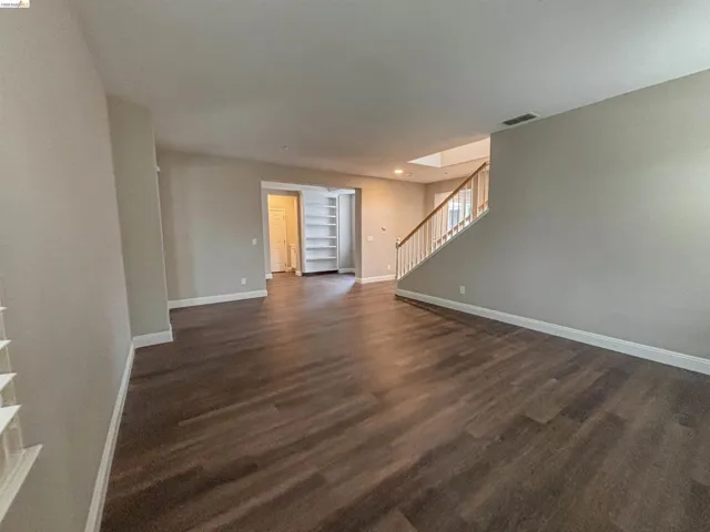 Unfurnished living room with dark wood-style flooring and recessed lighting