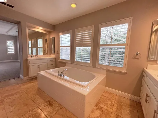 Bathroom featuring two vanities, a garden tub, and recessed lighting