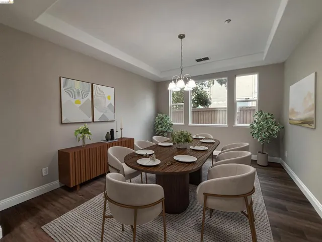 Dining area with a raised ceiling, suspended lighting, and dark wood-type flooring