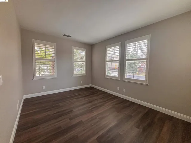 Empty room featuring baseboards and dark wood-style floors