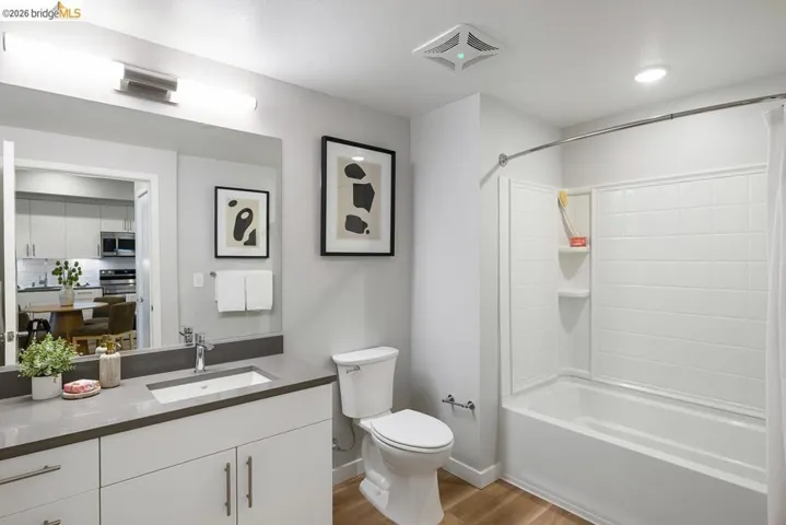 Bathroom with shower / bathtub combination with curtain, vanity, and light wood finished floors
