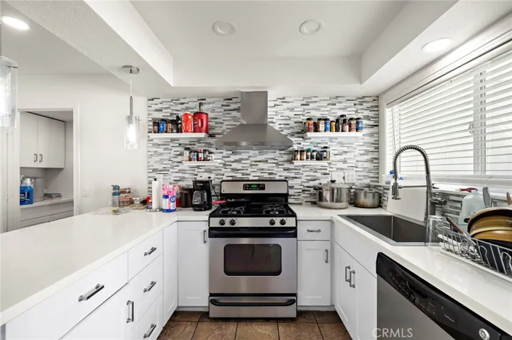 deep stainless sink with designer faucet, and stainless steel appliances including gas range, vent hood, dishwasher, and built-in microwave