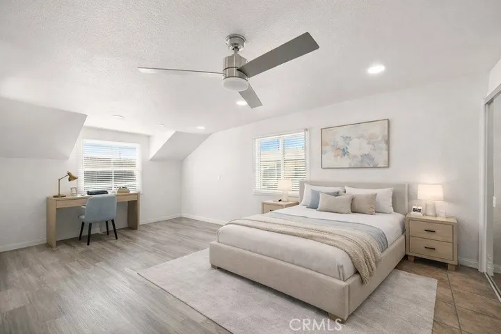 Virtually staged expansive upstairs primary suite offers wood laminate flooring, two mirrored closets