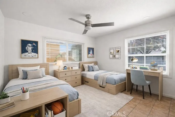 Virtually staged 2nd downstairs bedroom with ceiling fan tile floors