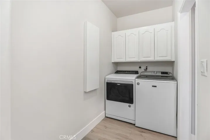 Downstairs laudry room with sink, ironing board, folding counter and linen storage.