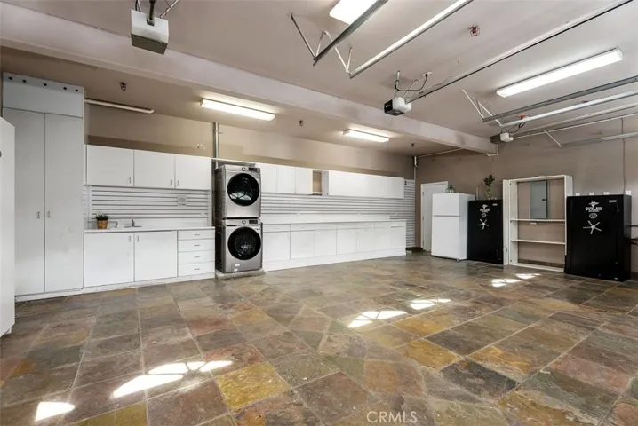 Three car garage with washer & dryer, sink, whole-house water purification system, reverse osmosis drinking water, wired for ADT security sytem, and plenty of cabinet space, drawers, extra refrigerator, lighting and slate flooring.  This garage is finished.  One safe can remain, one removed, up to the buyer.