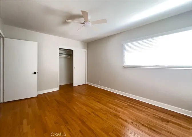 Bedroom 1 Alt view: Sun-drenched bedroom with two windows on adjacent walls, creating a wonderfully bright and airy atmosphere. Rich hardwood floors and a modern ceiling fan complete this cheerful room — ideal as a guest room, home office, or nursery.