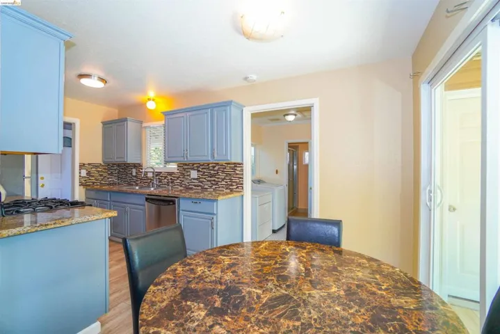 Kitchen featuring light stone counters, light wood-style flooring, tasteful backsplash, and dishwasher