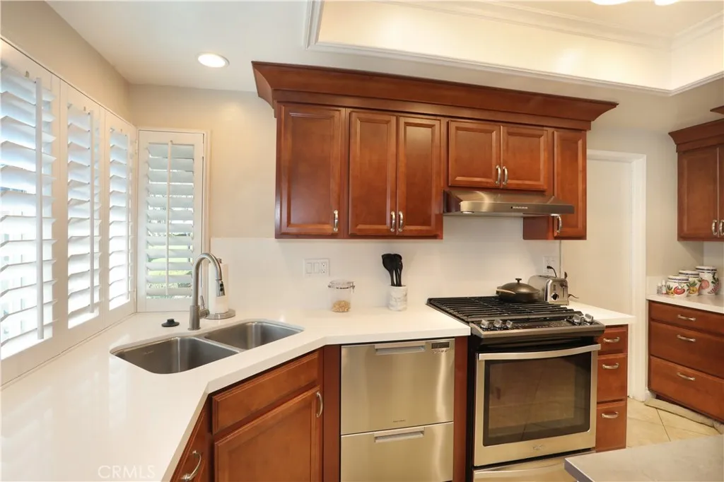 Stainless steel dual sinks and vent hood above the 5-burner stove.