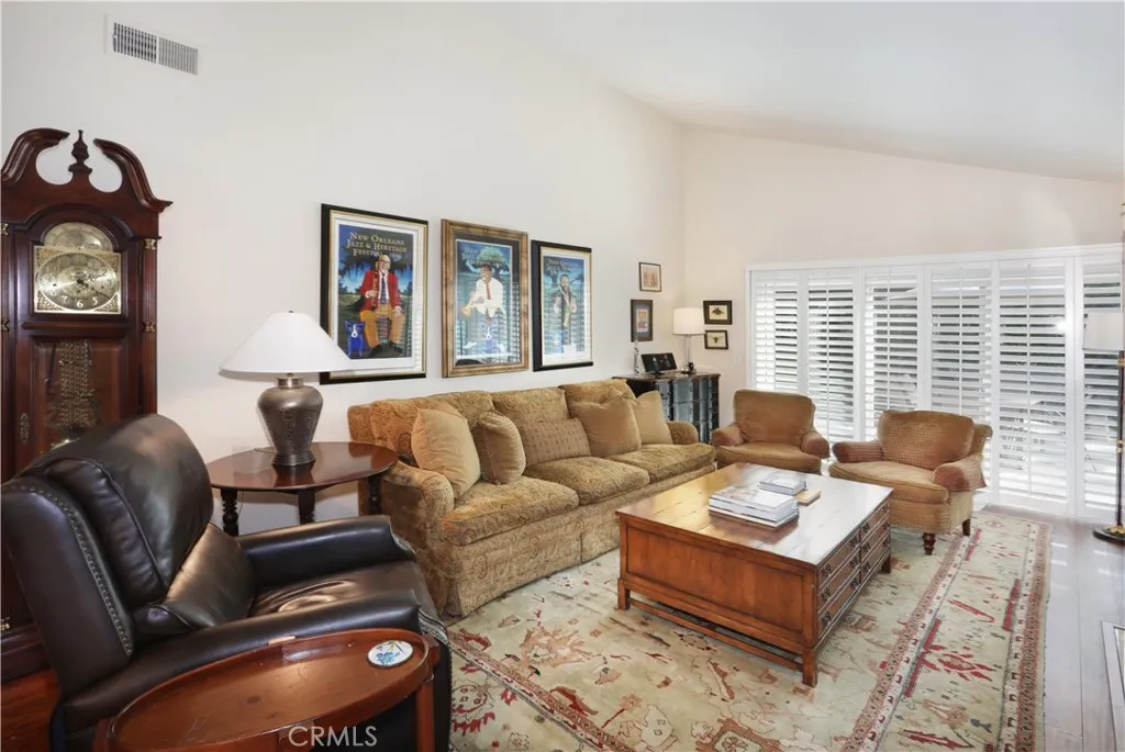 Living room has vaulted ceilings and plantation shutters cover the sliding glass doors.