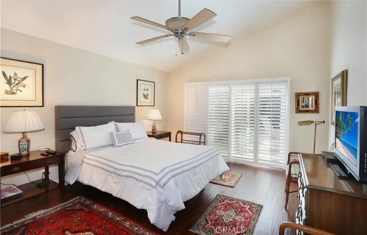 Primary bedroom has vaulted ceilings and sliding glass doors leading out to the patio. Plantation shutters throughout.