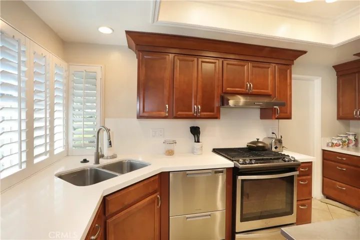 Stainless steel dual sinks and vent hood above the 5-burner stove.