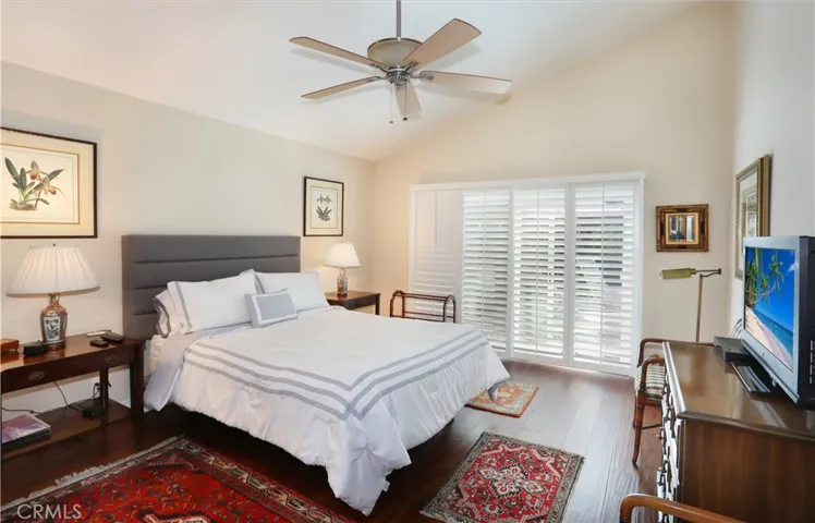 Primary bedroom has vaulted ceilings and sliding glass doors leading out to the patio. Plantation shutters throughout.