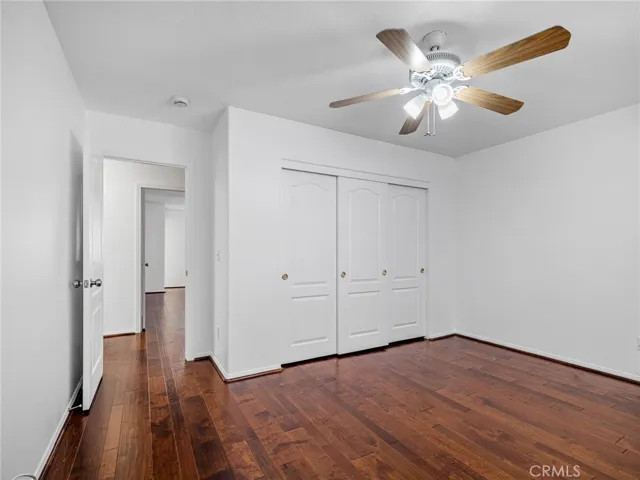 Comfortable bedroom with laminate flooring, ceiling fan, and fresh interior paint.