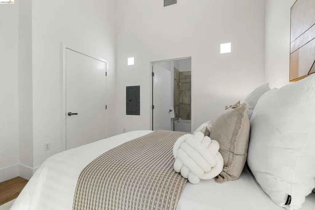 Bedroom featuring electric panel and connected bathroom