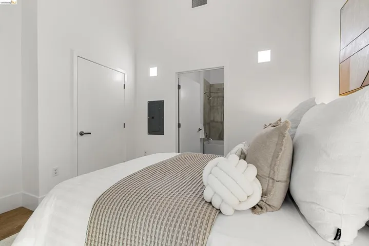 Bedroom featuring electric panel and connected bathroom