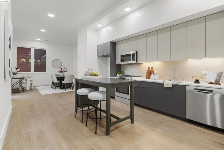Kitchen featuring modern cabinets, appliances with stainless steel finishes, light countertops, gray cabinets, and recessed lighting