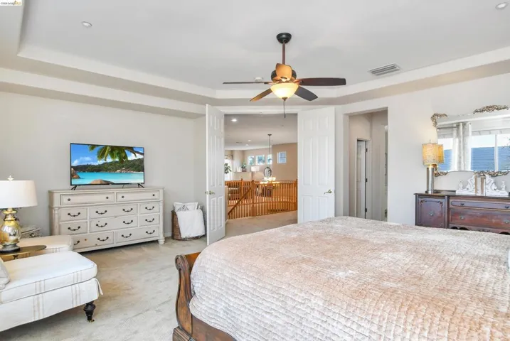 Bedroom featuring carpet floors, a raised ceiling, recessed lighting, and ceiling fan
