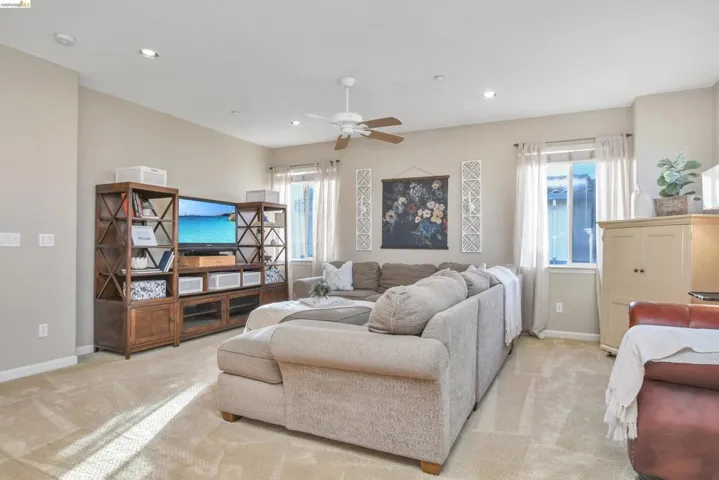 Living room with a ceiling fan, healthy amount of natural light, recessed lighting, and light colored carpet