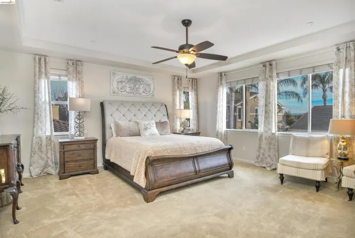 Bedroom with carpet floors, ceiling fan, and a raised ceiling