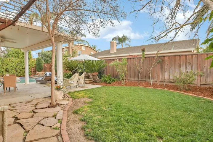 Fenced backyard with ceiling fan and a patio