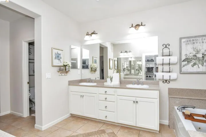 Full bathroom with double vanity, light tile patterned floors, and a whirlpool tub