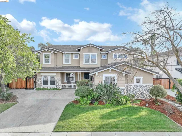 Craftsman-style house with stone siding, a porch, a tiled roof, and concrete driveway