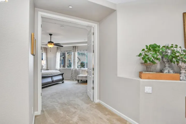 Hallway with light colored carpet and baseboards