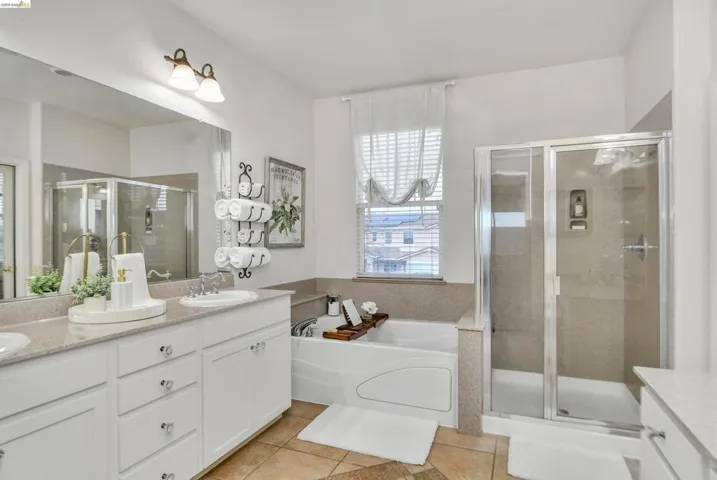 Bathroom with double vanity, a bath, a stall shower, and light tile patterned flooring